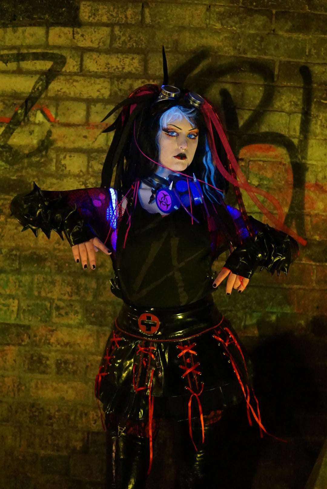 Cybergoth in post apocalyptic scene wearing red cyber falls and a black tank top with a black anarchy symbol on the front
