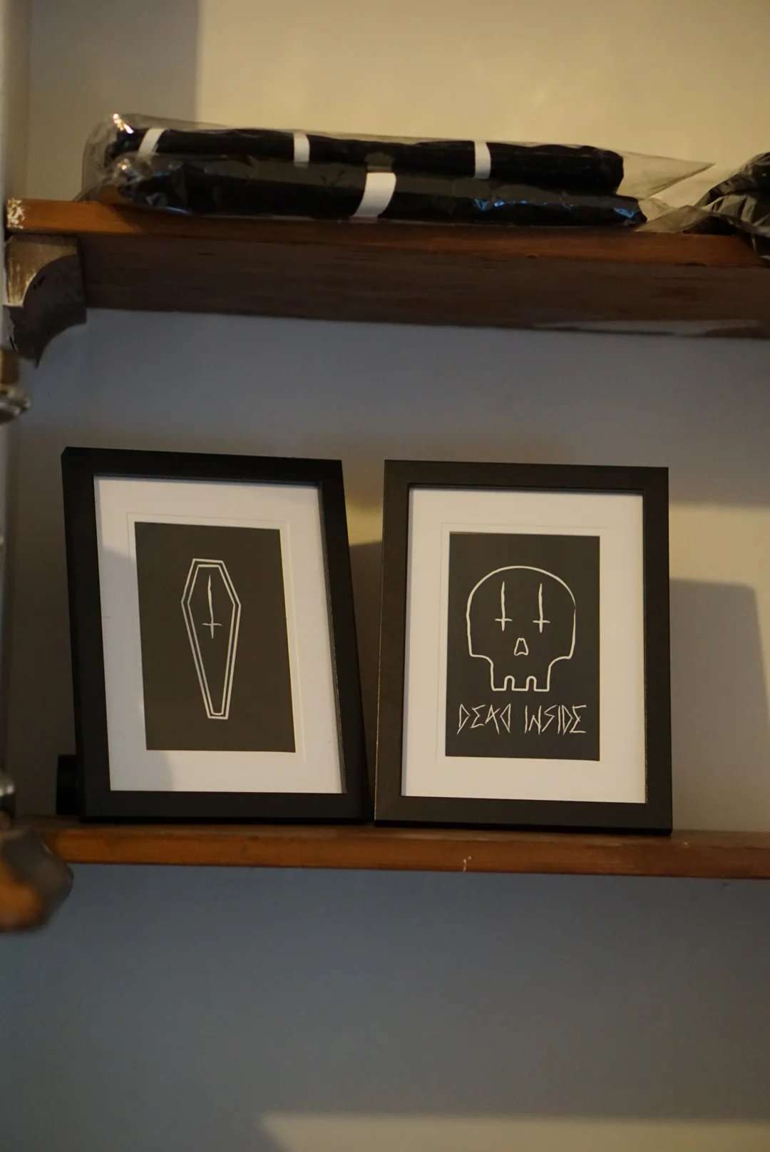 Pair of framed gothic style prints, one with coffin and the other with a skull with inverted crosses for eyes