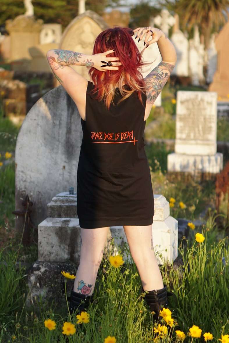 Back view of Queen of Hearts Tank/Dress styled as dress, showing bold red gothic text in dark alternative fashion setting.