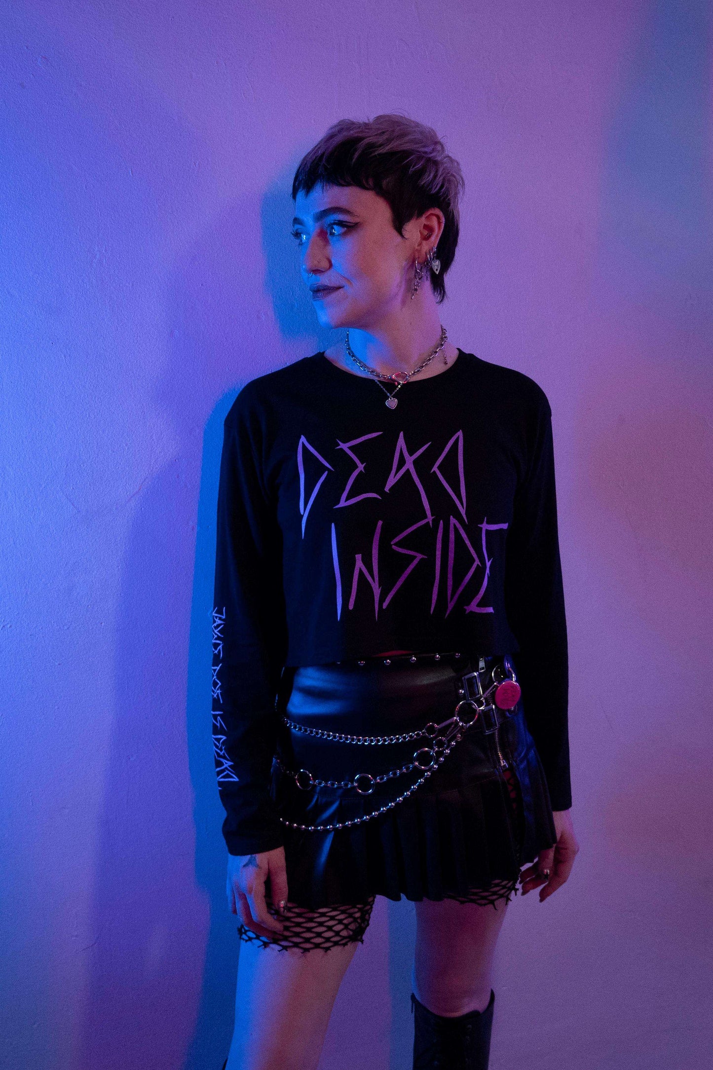 Alt emo goth girl wearing a long sleeve black cropped tshirt with the words dead inside printed on the front in purple gothic font. The arm has a jayne doe is dead