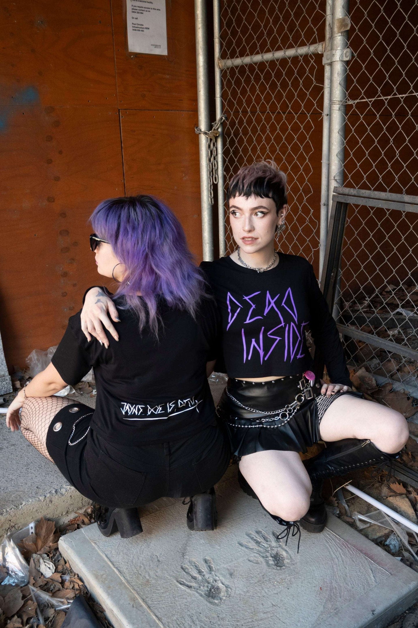 Goth emo alts girls wearing a long sleeve black cropped tshirt with the words dead inside printed on the front in purple gothic font. The arm has a jayne doe is dead