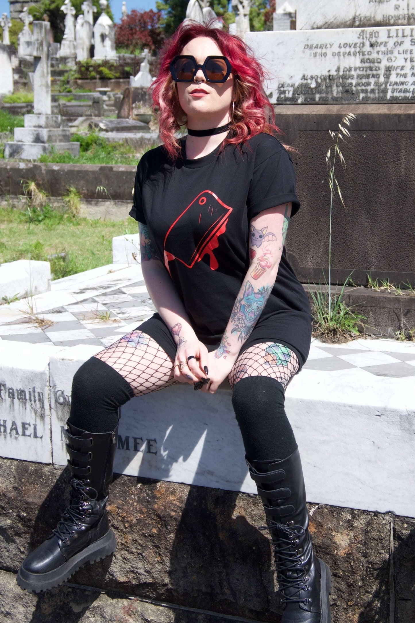 Off With Their Heads Xtra Long Tee / Dress styled as a t-shirt dress with bold red graphic print, worn with fishnets and combat boots in a gothic cemetery setting.