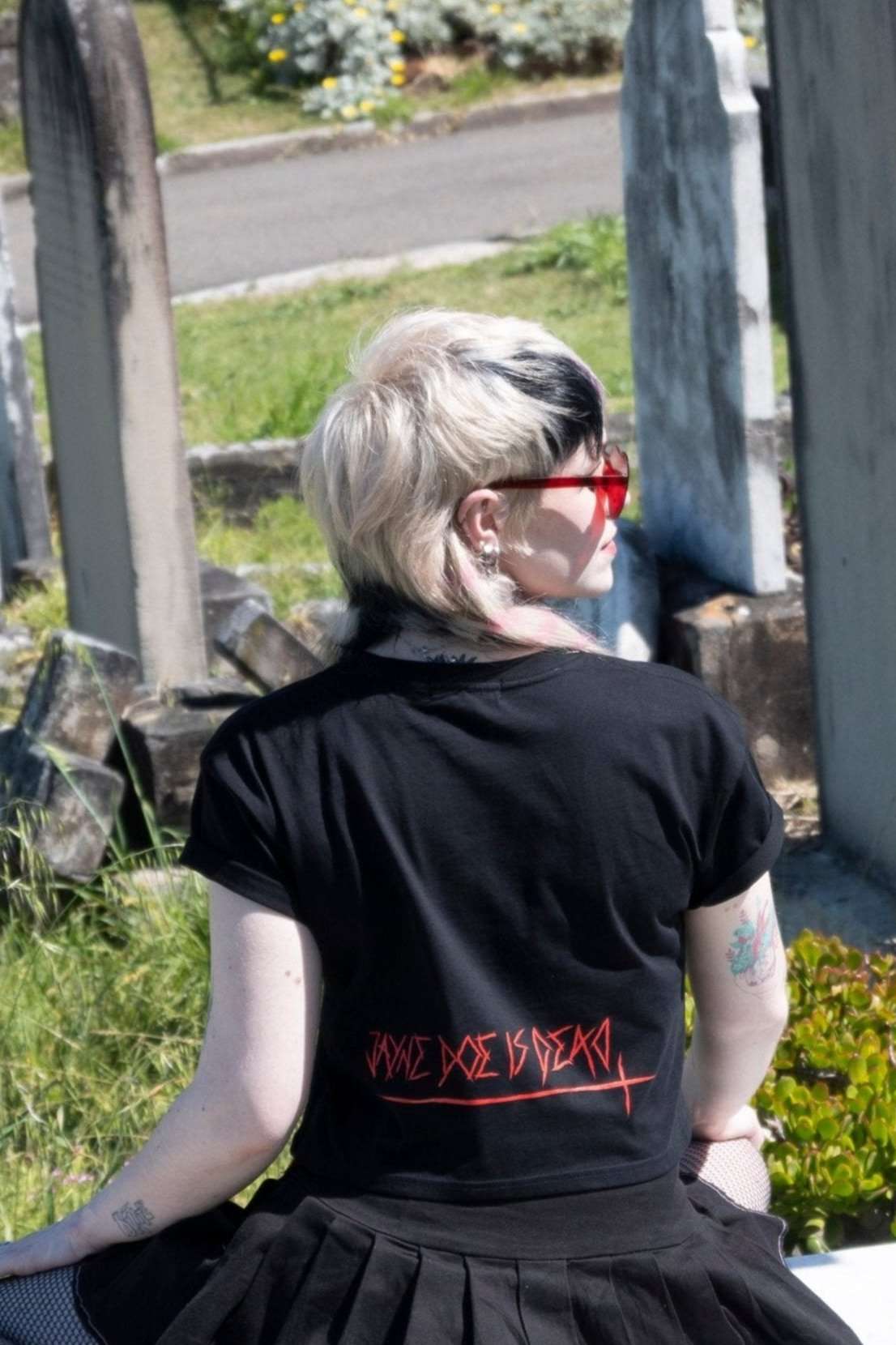 Back view of Off with their Heads Cropped Tee showing 'Jayne Doe is Dead' red gothic text, styled in alternative fashion at a cemetery location.