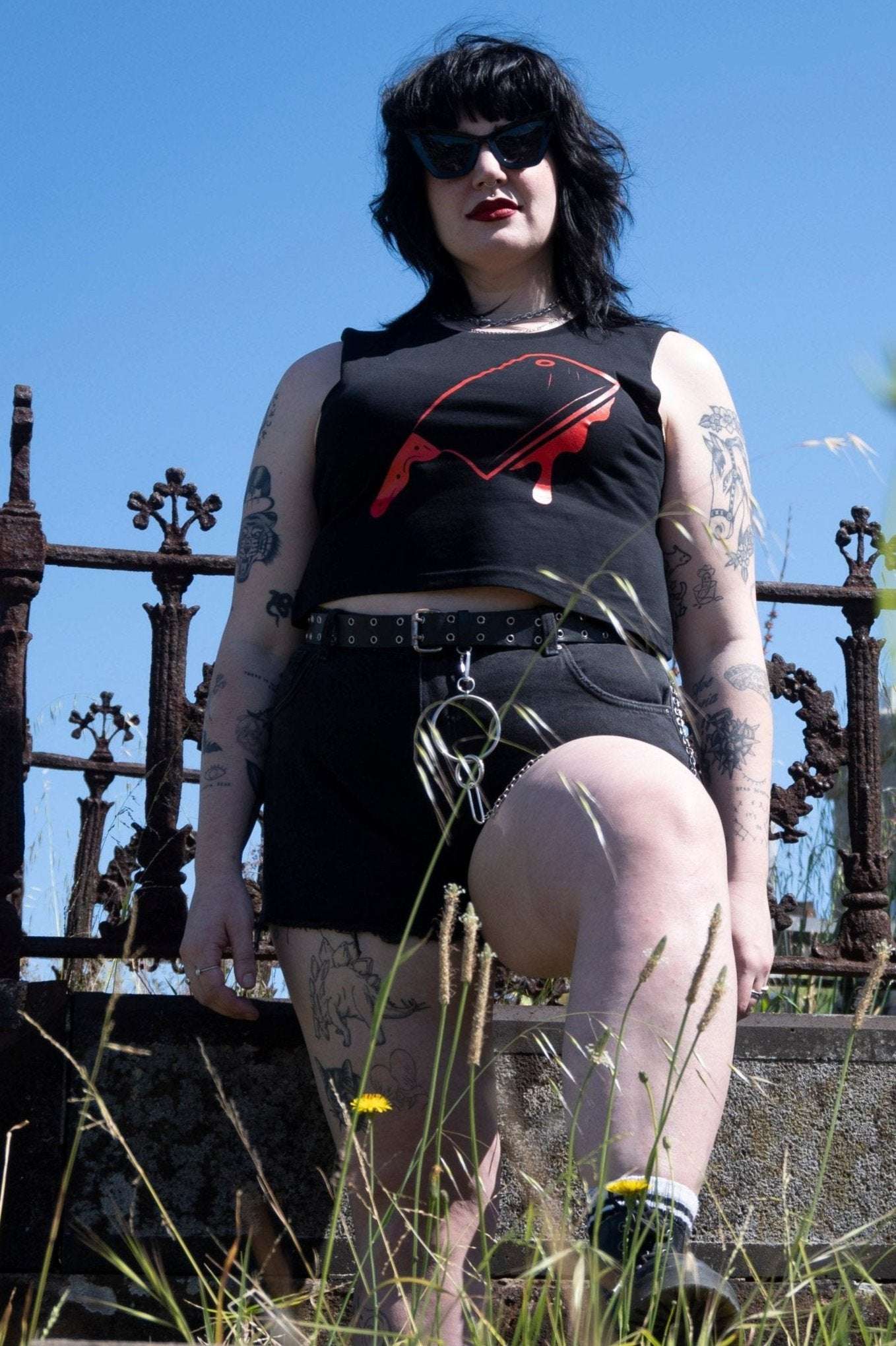 Off with their Heads Cropped Tank styled with black high-waisted shorts and belt, featuring red cleaver print in alt streetwear look.