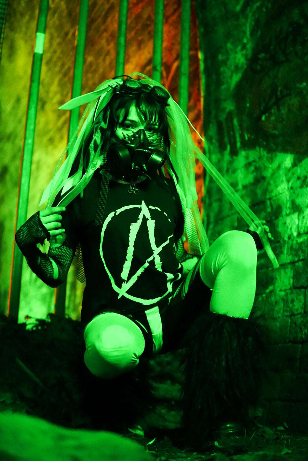 Cybergoth girl in post apocalyptic scene, wearing a black cropped tshirt with a big white A (for anarchy) print on the front