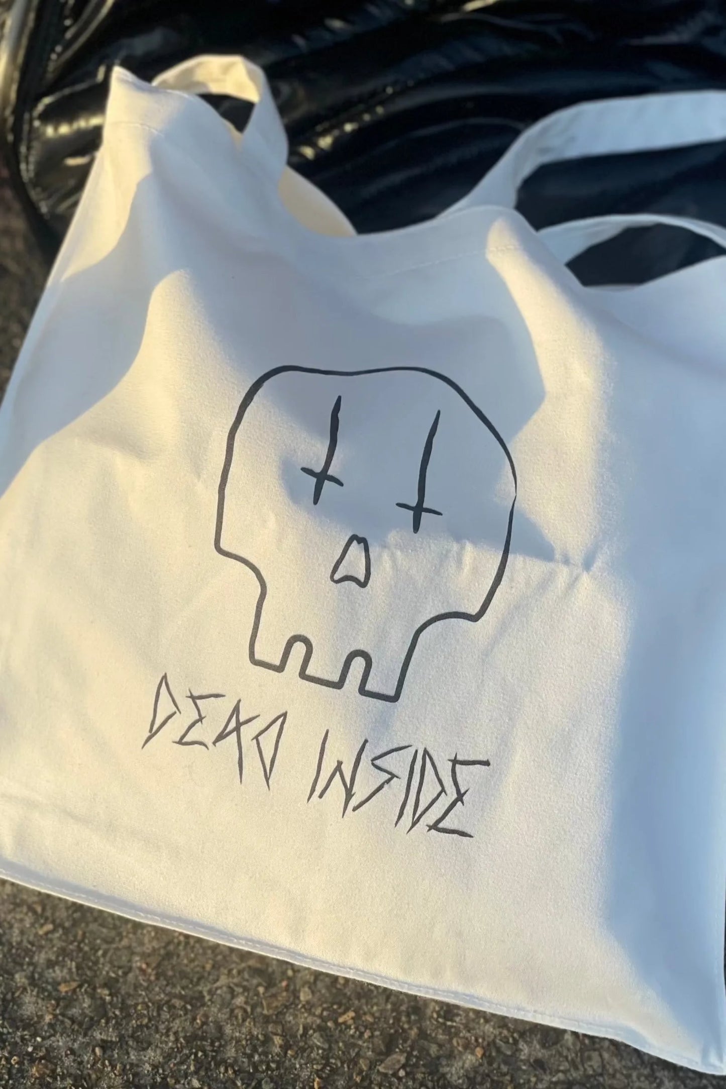 White cotton tote bag with black printed skull with the words dead inside underneath