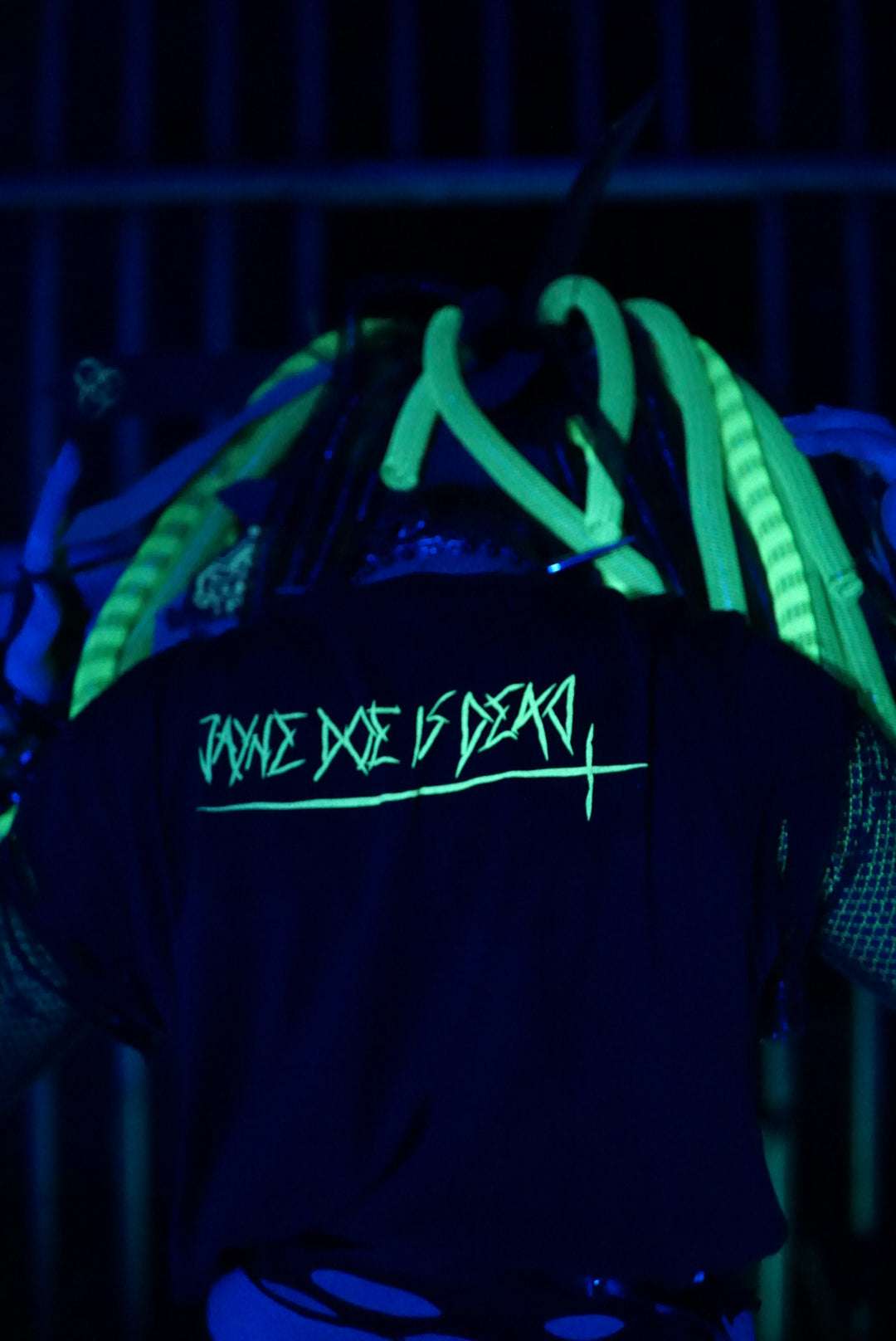 Cyber goth dressed in black cropped tshirt with Jayne doe is dead logo print in UV glowing toxic green